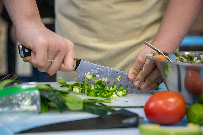 A closeup of hands chopping a jalapeno