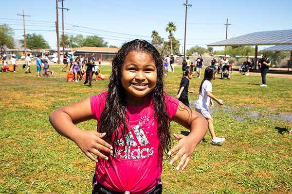 A girl in a pink shirt smiles after getting sprayed by the fire department