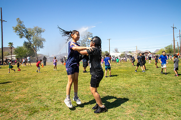 Two girls jump around in the spray of the fire department hose