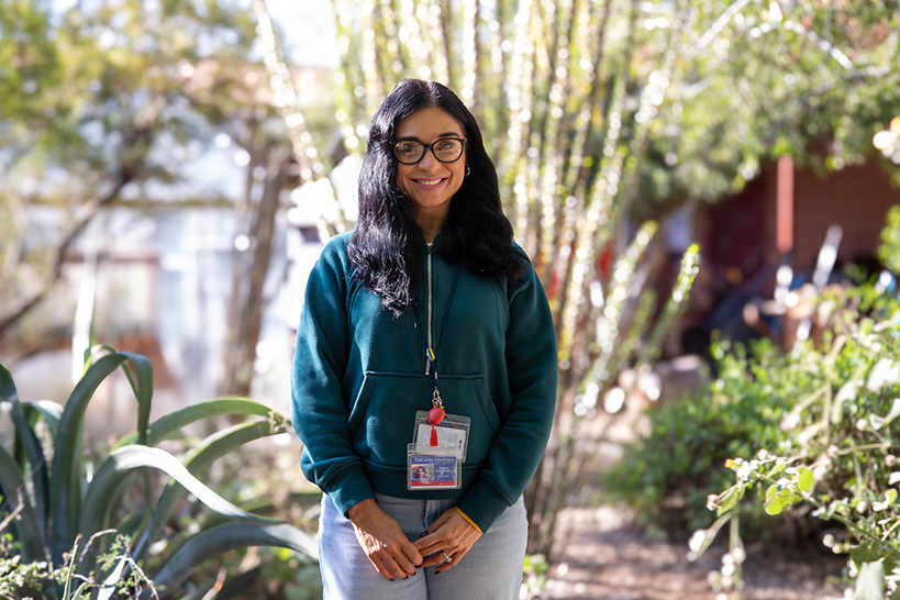 A woman wearing glasses smiles in the school garden