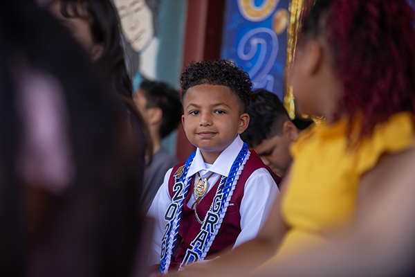 A little boy wearing a graduation stole