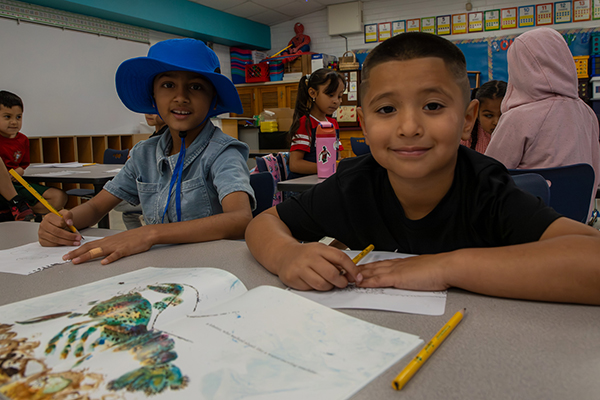 A girl and a boy work on an assignment at their desk