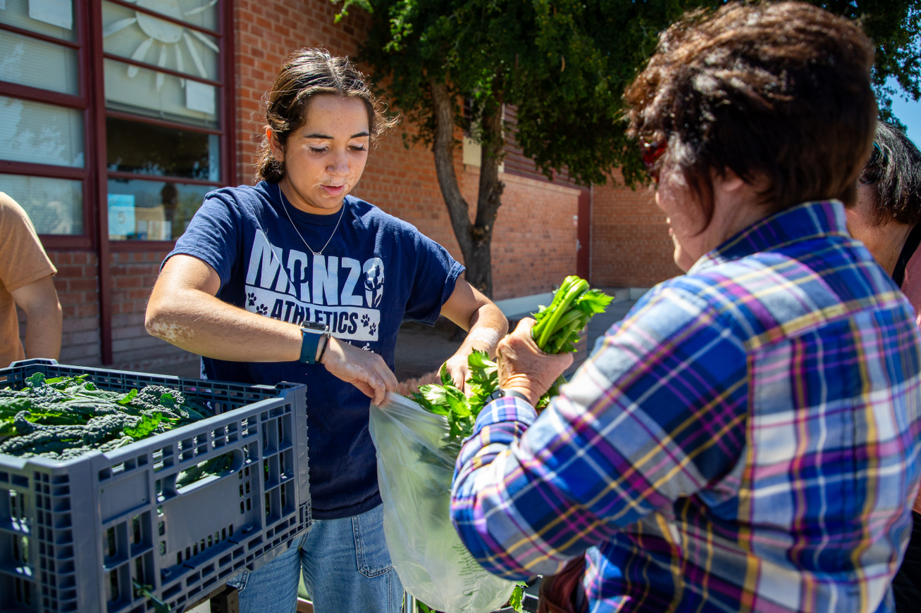 A Manzo staff member bags up veggies for a woman
